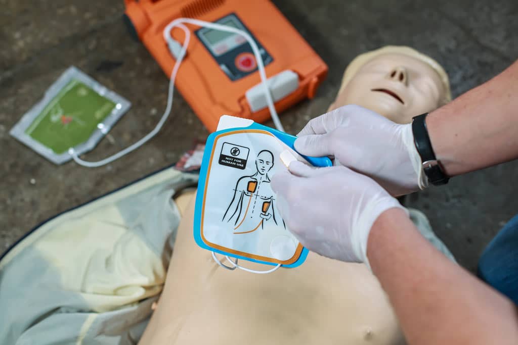 Person unsticking pads from AED to stick to a dummy